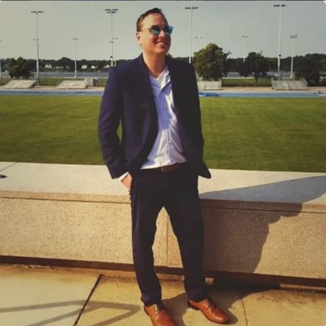 Andrew in a navy blazer at a stadium